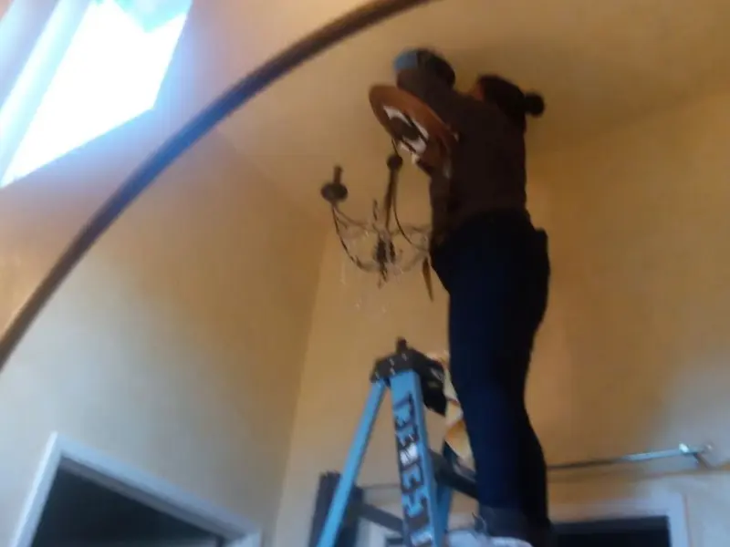 Electrician installing a chandelier in a Belmont residence